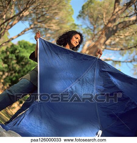 Stock Image - Woman setting up tent. Fotosearch