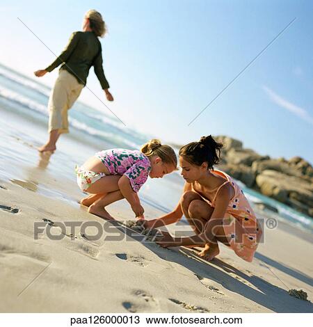 Woman walking on beach, children digging in sand View Large Photo Image Stock Image - Woman walking on beach, children digging in sand. Fotosearch