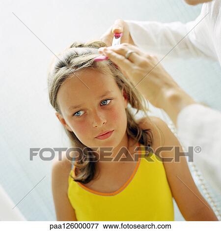 Stock Photo - Woman's hands fixing child's hair, close-up. Fotosearch