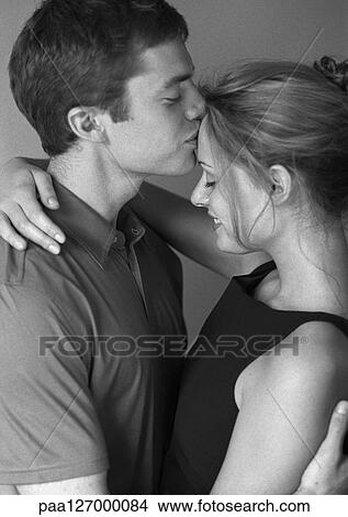 Couple embracing, man kissing woman's forehead, side view, b&w View Large Photo Image Picture - Couple embracing, man kissing woman's forehead, side view, b&w. Fotosearch
