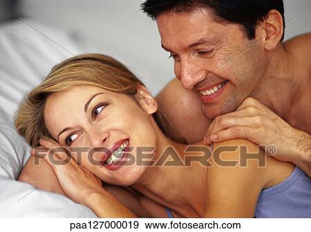 Couple in bed, smiling, close-up View Large Photo Image Stock Photo - Couple in bed, smiling, close-up. Fotosearch