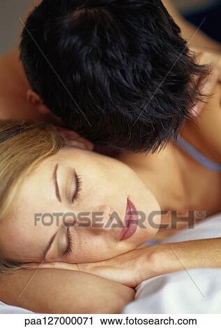 Stock Image - Couple lying on bed, close-up. Fotosearch