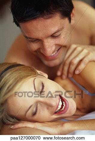 Couple lying on bed, smiling View Large Photo Image Stock Image - Couple lying on bed, smiling. Fotosearch