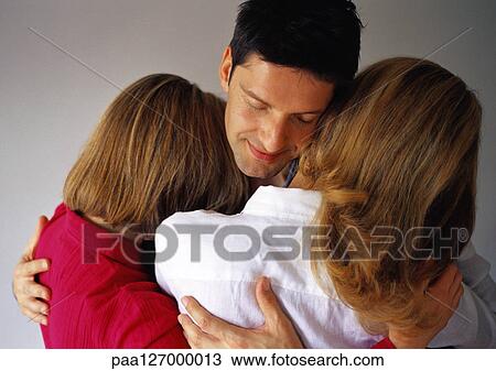 Man hugging two women, eyes closed View Large Photo Image Stock Image - Man hugging two women, eyes closed. Fotosearch