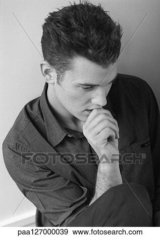 Stock Photo - Man with hand in front of mouth, portrait, b&w. Fotosearch