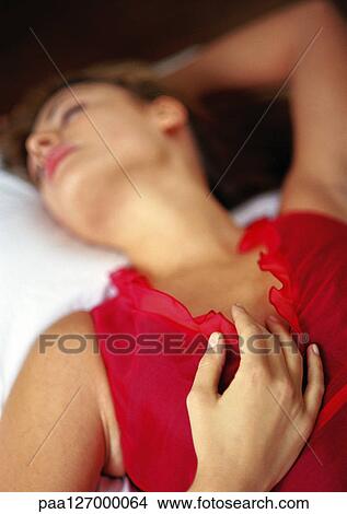 Woman lying in bed with hand on chest View Large Photo Image Picture - Woman lying in bed with hand on chest. Fotosearch