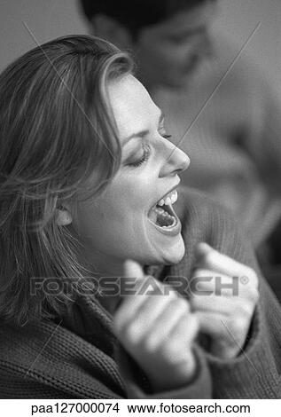 Woman shouting with joy, man in background, close-up, b&w View Large Photo Image Picture - Woman shouting with joy, man in background, close-up, b&w. Fotosearch