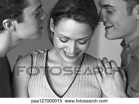 Stock Photography - Woman standing between two men, both men whispering to woman, close-up, b&w. Fotosearch