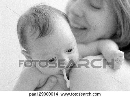 Infant spitting up on mother's shoulder, close-up, b&w View Large Photo Image Picture - Infant spitting up on mother's shoulder, close-up, b&w. Fotosearch