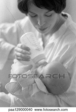 Stock Image - Mother bottle feeding infant, b&w. Fotosearch