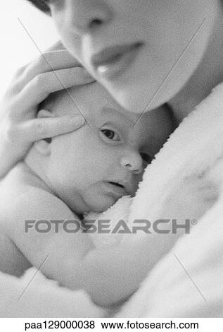 Stock Photo - Mother holding infant against chest, close-up, b&w. Fotosearch