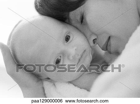 Stock Photograph - Mother holding infant against face, close-up, b&w. Fotosearch