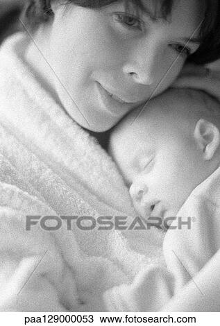 Stock Image - Mother holding sleeping infant against chest, b&w. Fotosearch