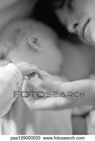Mother lying with infant, playing with infant's hand, close-up, b&w View Large Photo Image Stock Image - Mother lying with infant, playing with infant's hand, close-up, b&w. Fotosearch