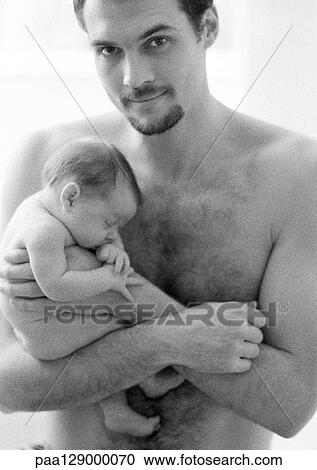 Stock Image - Topless father holding sleeping infant, looking at camera, b&w. Fotosearch