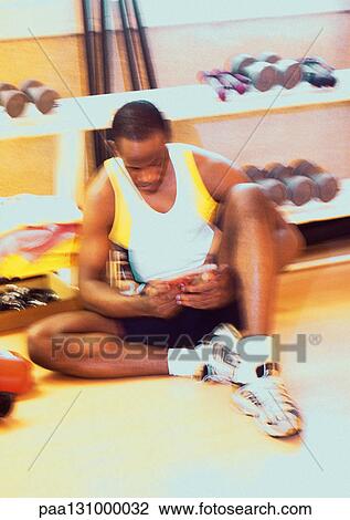 Man sitting next to barbell rack in gym View Large Photo Image Stock Image - Man sitting next to barbell rack in gym. Fotosearch