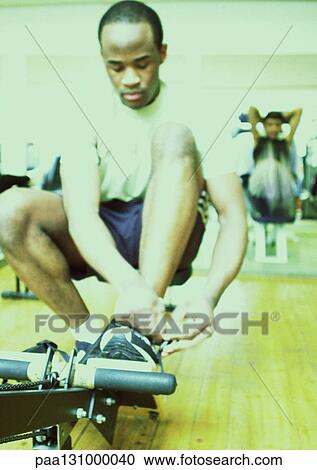 Man tying shoe laces in gym View Large Photo Image Stock Image - Man tying shoe laces in gym. Fotosearch