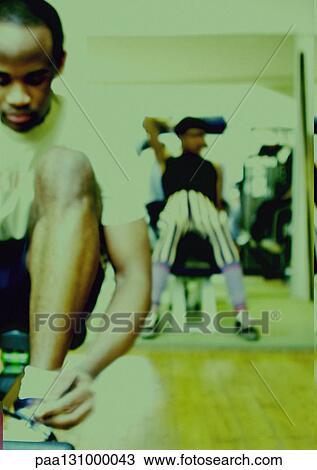 Man tying shoe laces in gym View Large Photo Image Stock Image - Man tying shoe laces in gym. Fotosearch