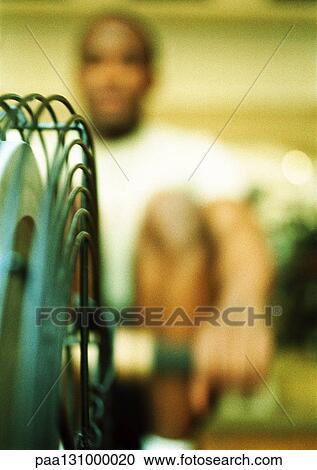 Stock Image - Man using rowing machine. Fotosearch