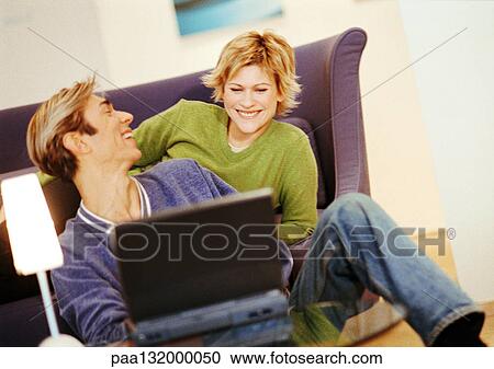 Couple smiling, using laptop View Large Photo Image Stock Image - Couple smiling, using laptop. Fotosearch