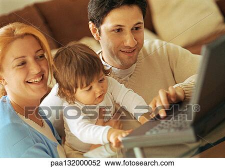 Man and woman with baby sitting, looking at laptop View Large Photo Image Stock Image - Man and woman with baby sitting, looking at laptop. Fotosearch