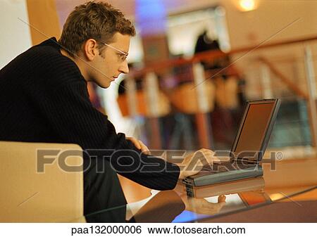 Stock Photograph - Man using laptop, side view.. Fotosearch