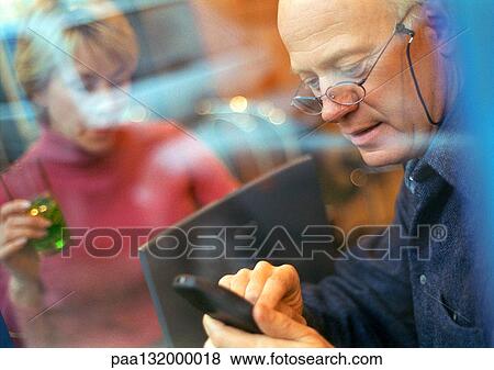 Mature couple, man using cell phone, woman using laptop. View Large Photo Image Stock Photo - Mature couple, man using cell phone, woman using laptop.. Fotosearch