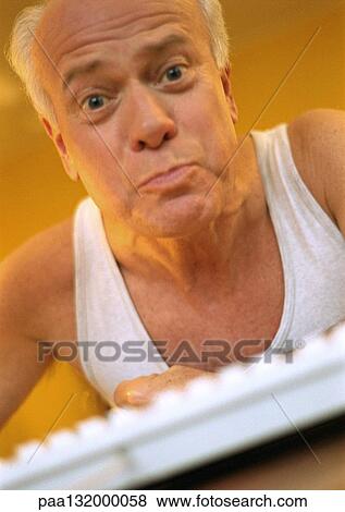 Mature man looking into camera, computer keyboard in foreground, portrait. View Large Photo Image Stock Photo - Mature man looking into camera, computer keyboard in foreground, portrait.. Fotosearch