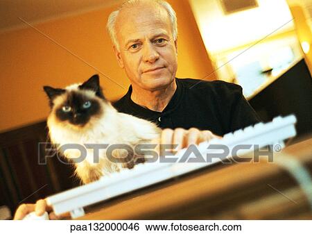 Mature man with Persian cat and hand on computer keyboard, looking into camera, portrait. View Large Photo Image Stock Photograph - Mature man with Persian cat and hand on computer keyboard, looking into camera, portrait.. Fotosearch