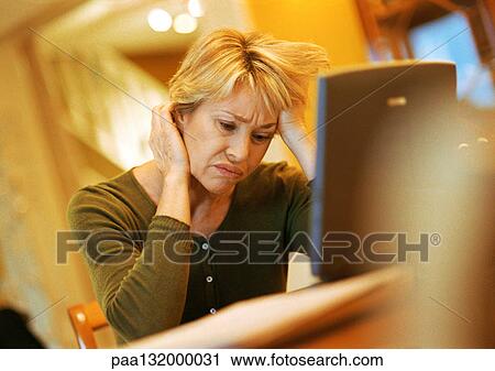 Mature woman using laptop, looking agitated View Large Photo Image Stock Image - Mature woman using laptop, looking agitated. Fotosearch