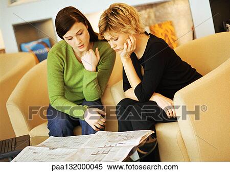 Stock Photography - Two women sitting, reading newspaper.. Fotosearch