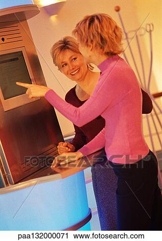 Two women standing in front of computer, smiling View Large Photo Image Stock Image - Two women standing in front of computer, smiling. Fotosearch