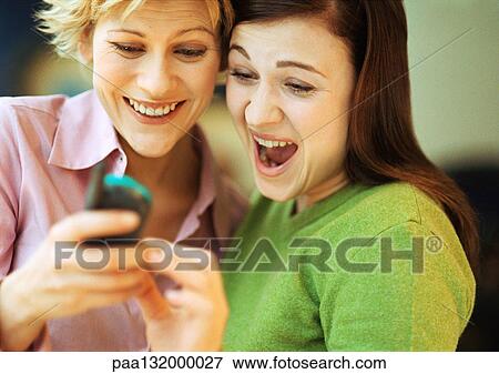 Stock Photo - Two young women using cell phone, portrait.. Fotosearch