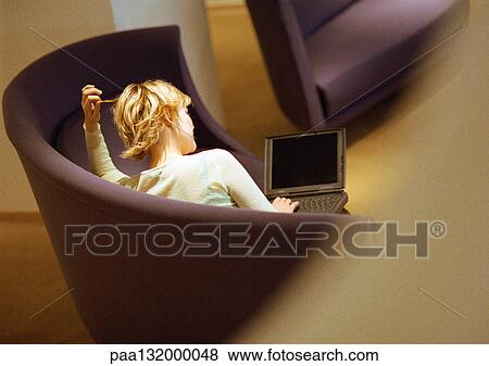 Woman sitting on sofa using laptop, rear view. View Large Photo Image Stock Photo - Woman sitting on sofa using laptop, rear view.. Fotosearch