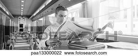 Businessman sitting in train reading newspaper, b&w, panoramic view View Large Photo Image Stock Image - Businessman sitting in train reading newspaper, b&w, panoramic view. Fotosearch