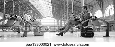 Businesspeople sitting in train station, b&w, panoramic view View Large Photo Image Stock Image - Businesspeople sitting in train station, b&w, panoramic view. Fotosearch