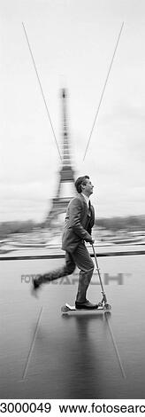 Man riding push scooter on esplanade in front of Eiffel Tower, b&w, vertical View Large Photo Image Stock Photo - Man riding push scooter on esplanade in front of Eiffel Tower, b&w, vertical. Fotosearch