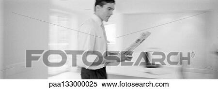 Man walking in room reading newspaper, b&w, panoramic view View Large Photo Image Stock Photography - Man walking in room reading newspaper, b&w, panoramic view. Fotosearch