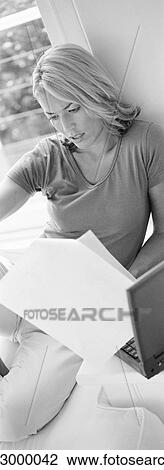 Woman lounging, looking at documents near laptop, b&w, vertical View Large Photo Image Stock Image - Woman lounging, looking at documents near laptop, b&w, vertical. Fotosearch