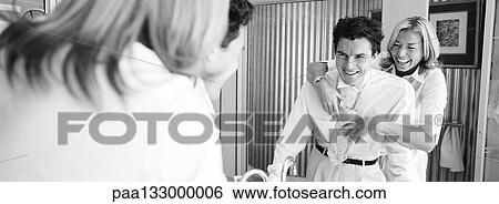 Woman standing behind man tying man's tie, laughing, b&w, panoramic view View Large Photo Image Stock Photograph - Woman standing behind man tying man's tie, laughing, b&w, panoramic view. Fotosearch