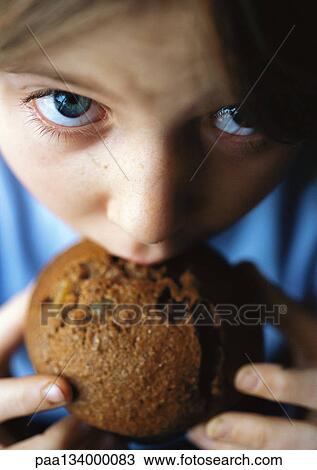 Stock Image - Child eating muffin, close-up.. Fotosearch