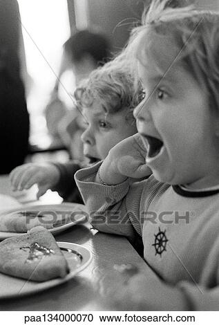 Children sitting at table, mouths open, side view, b&w. View Large Photo Image Stock Image - Children sitting at table, mouths open, side view, b&w.. Fotosearch