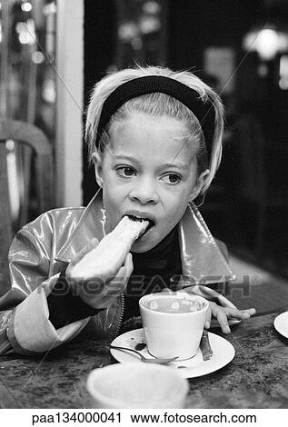 Stock Image - Girl eating bread, drinking hot chocolate, b&w.. Fotosearch