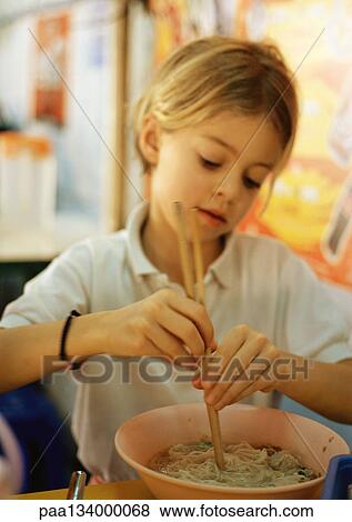 Girl using chopsticks in bowl of noodles, portrait. View Large Photo Image Stock Photo - Girl using chopsticks in bowl of noodles, portrait.. Fotosearch