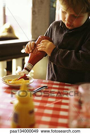 Little boy behind table with red and white checked tablecloth, squeezing ketchup onto french fries View Large Photo Image Stock Photo - Little boy behind table with red and white checked tablecloth, squeezing ketchup onto french fries. Fotosearch