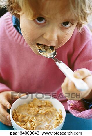 Little girl eating cereal, looking into camera, portrait. View Large Photo Image Stock Image - Little girl eating cereal, looking into camera, portrait.. Fotosearch