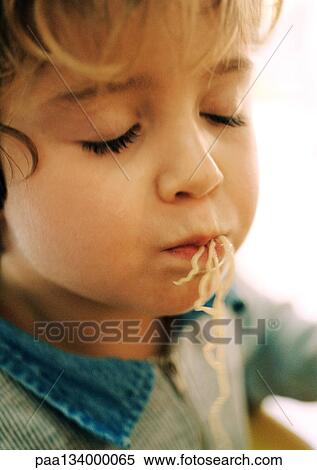 Stock Photography - Little girl eating noodles, portrait.. Fotosearch