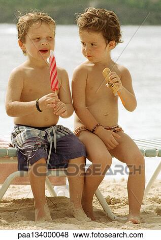 Two children eating popsicles on beach. View Large Photo Image Stock Photo - Two children eating popsicles on beach.. Fotosearch