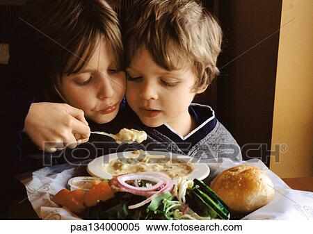 Young boy helping younger brother eat, portrait. View Large Photo Image Stock Photography - Young boy helping younger brother eat, portrait.. Fotosearch