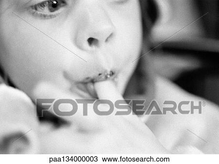 Stock Image - Young child eating, finger in mouth, close-up, b&w.. Fotosearch